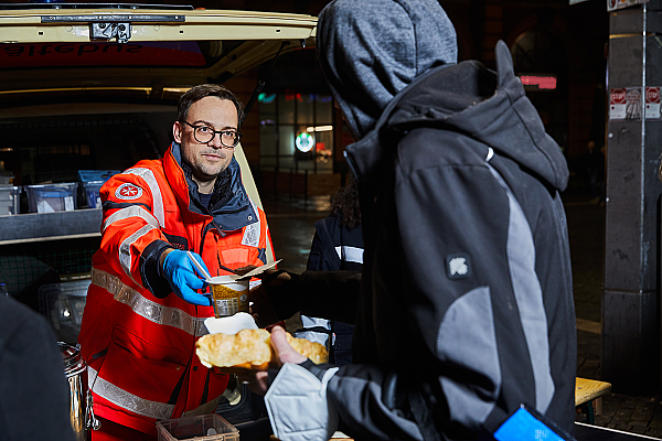 Ein Helfender des Kältebus gibt Essen an eine bedürftige Person aus