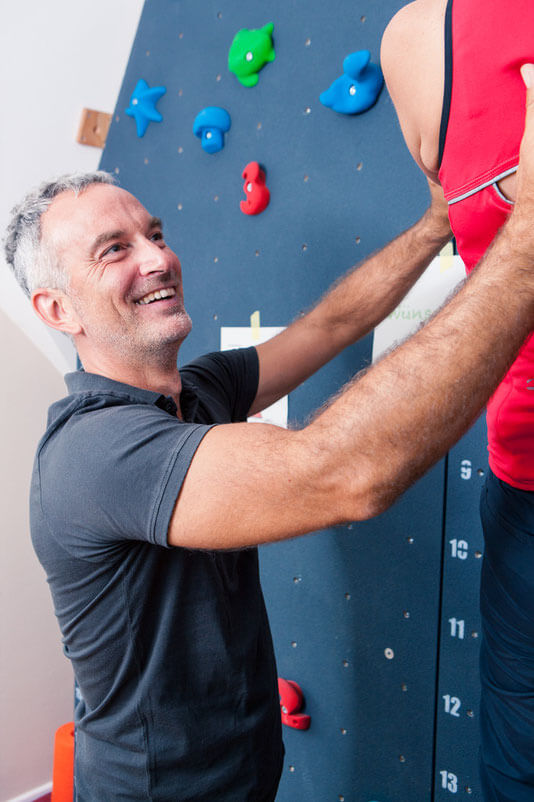Mann an Kletterwand mit Lächeln im Gesicht 