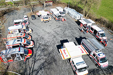 Luftaufnahme von Rettungs- und Einsatzfahrzeugen, kreisförmig auf einem Parkplatz aufgestellt.