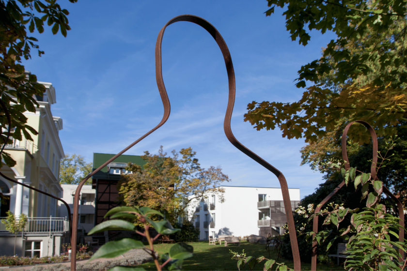 Garten der Klinik am Korso - im Vordergrund zu sehen ist der Anschnitt einer Gartenskulptur die den Umriss einer Person zeigt