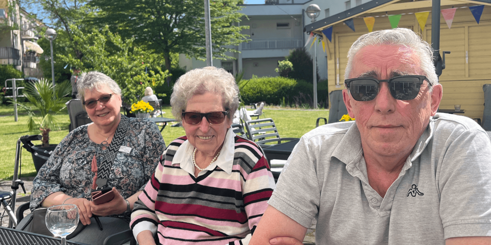 drei Personen mit Sonnenbrillen an einem Gartentisch