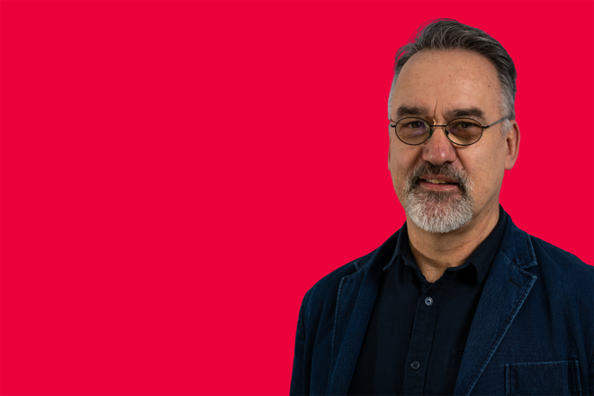 Portrait eines Mitarbeiters vor rotem Hintergrund