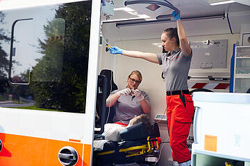 Versorgung im Rettungsdienst: Team legt Infusion bei Patientin im Krankentransport.