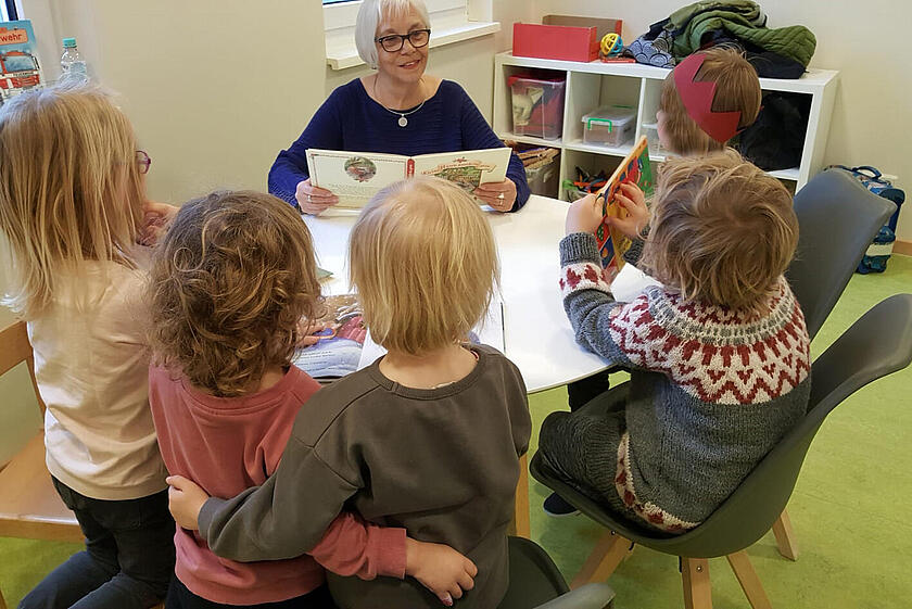 Eine ältere Dame liest Kindern etwas vor