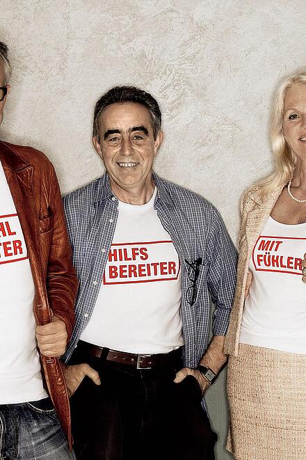 Drei Johanniter-Fördermitglieder tragen T-Shirts mit der Aufschrift "Wohltäter", "Hilfbereiter", "Mitfühler".