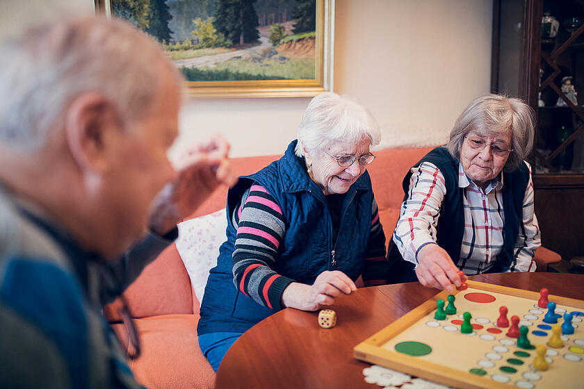 zwei Damen und ein Herr spielen Mensch-ärgere-dich-nicht