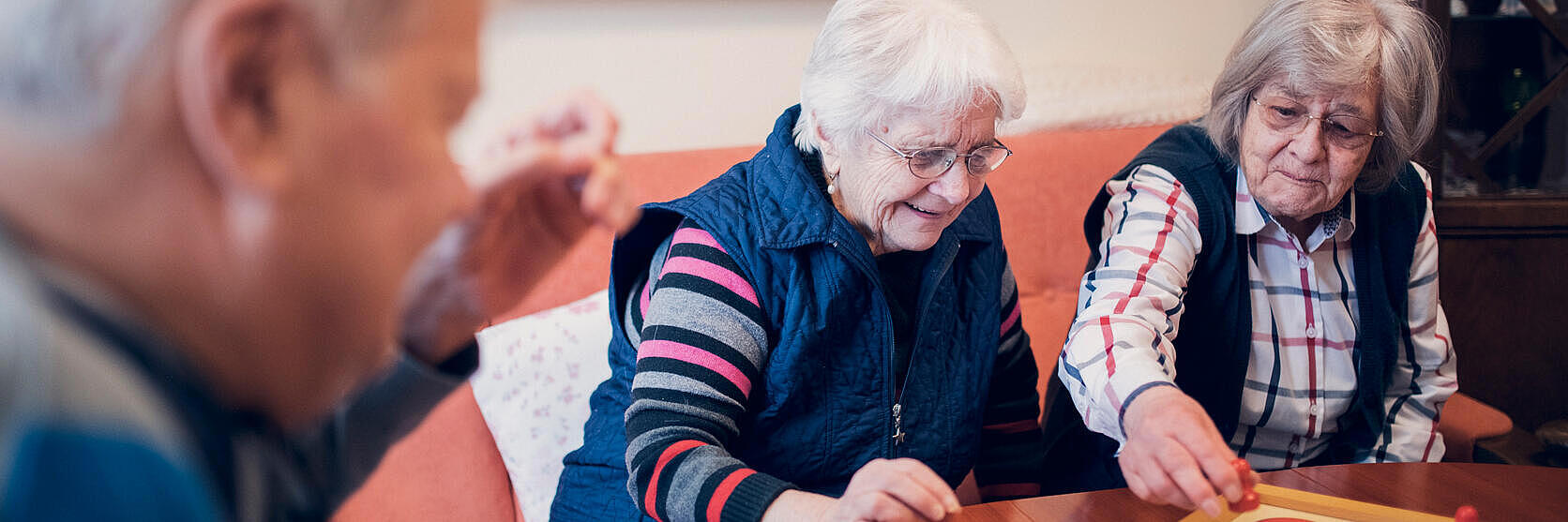 zwei Damen und ein Herr spielen Mensch-ärgere-dich-nicht