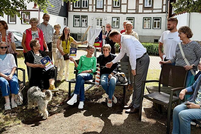 Gruppenfoto Menschen um neue Plauderbank herum
