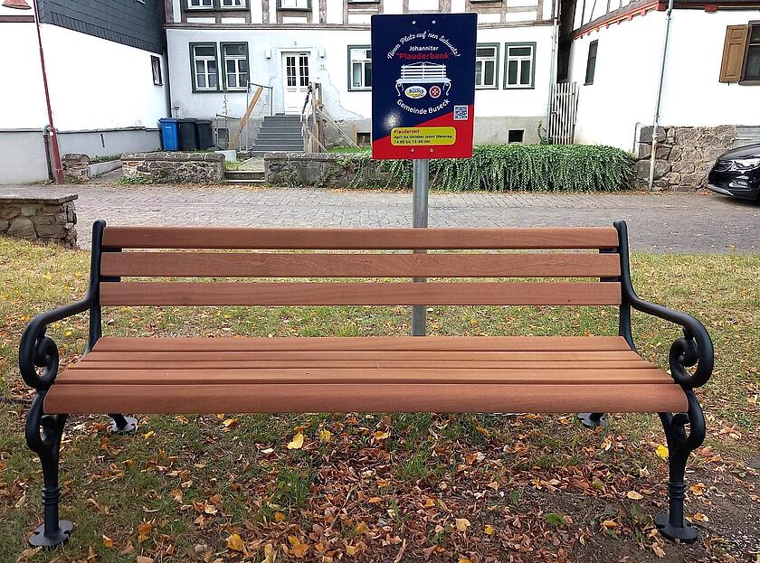 Holzbank mit Plauderbankschild im Hintergrund