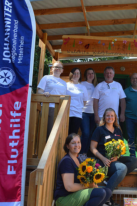 Gruppenfoto: Mitarbeiter vor dem Bauwagen der Waldkita in Rech