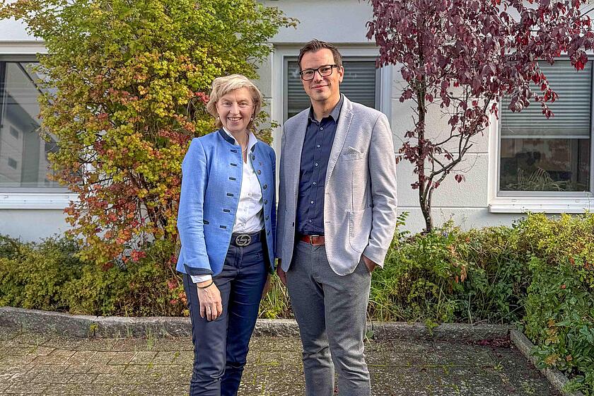 Anette Röttger und Yonathan Arnold stehen vor dem Hauptgebäude und lächeln in die Kamera.