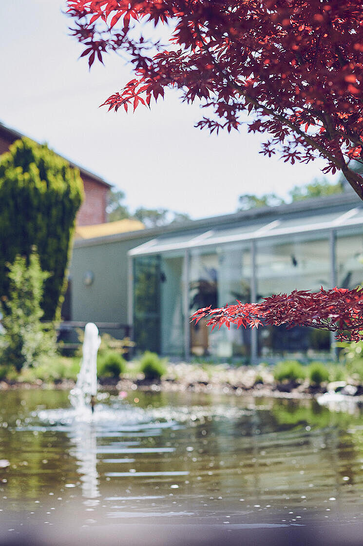Über einen kleinen Gartenteich schaut man auf das Johanniterhaus Celle