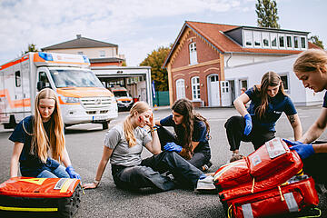 Gruppe von Schulsanitätern neben einem Rettungswagen bei einer Outdoor‑Übung.