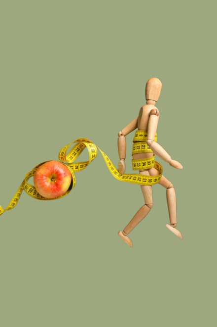 Symbolbild: Holzfigur im Sprint und Apfel je umschlungen von einem Maßband als Symbol für Sport-Anorexie Sport Bulimie und sonstige Essstörungen