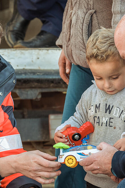Helferin verteilt Geschenk an Kind im Rahmen des Johanniter-Weihnachtstruckers