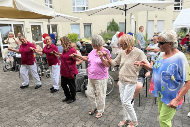 Eine Reihe Menschen hält sich tanzend an den Händen.