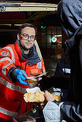 Ein Helfender des Kältebus gibt Essen an eine bedürftige Person aus