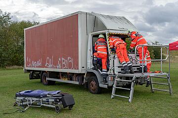 Mehrere Einsatzkräfte versorgen einen Darsteller im Fahrerhaus eines Lkw.