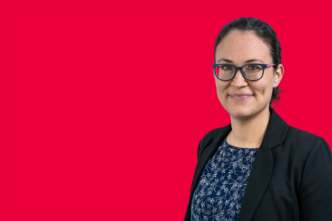 Portrait einer Mitarbeiterin vor rotem Hintergrund