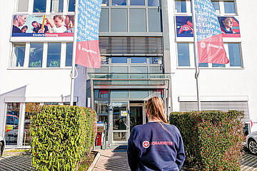 Eine Johanniterin steht vor dem Eingang zur Johanniter Regionalgeschäftsstelle Puchheim.