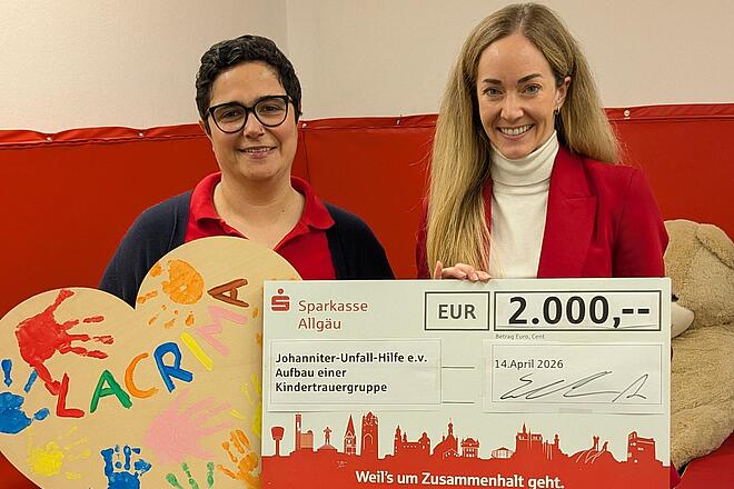 Anna Schönmetzler von der übergibt einen symbolischen Spendenscheck über 2.000 Euro an Viviana Boy von der für das Trauerbegleitungsangebot Lacrima in Kempten. Die Spende unterstützt die Begleitung trauernder Kinder, Jugendlicher und Angehöriger.