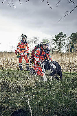 Zwei Frauen mit Einsatzkleidung und ein Hund im Gelände