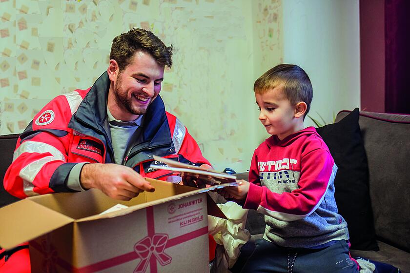 Kind packt Weihnachtstrucker-Paket aus. 