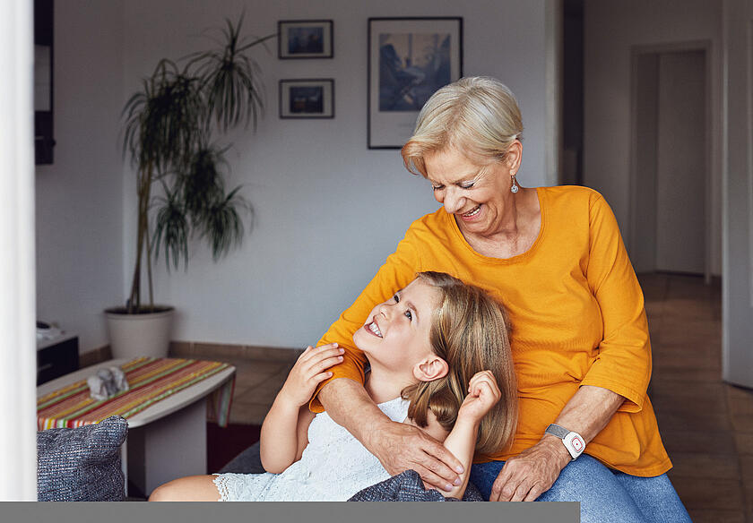 Hausnotruf Imagefoto Oma mit Enkelin, Hausnotrufgerät am Handgelenk