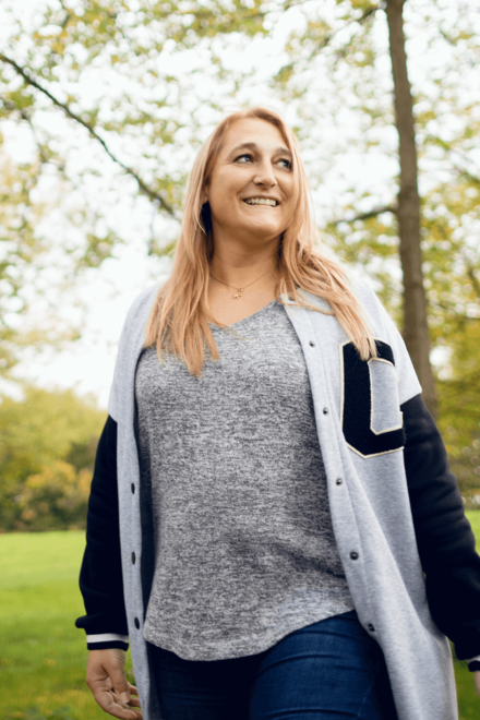 Eine Frau in einer Parkanlage. Sie hat lange rötlich-blonde Haare und blickt seitlich vom Fotografen weg. 