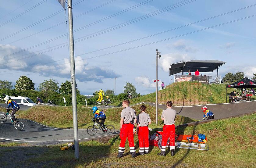 Drei Ehrenamtliche beim Sanitätsdienst beim BMX-Turnier am Rand der Strecke